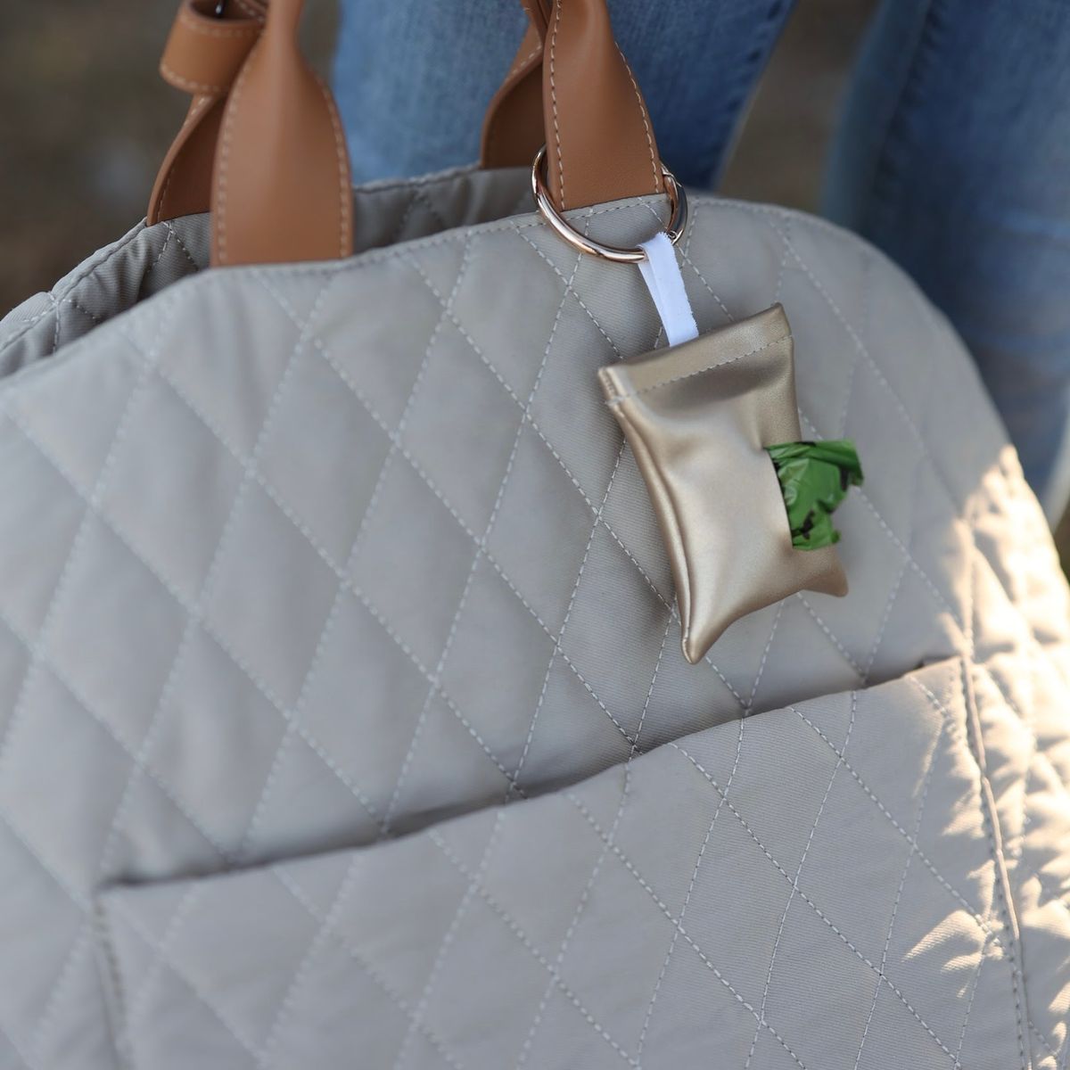 Gold poop bag pouch attached to the 3-in-1 dog travel bag via a sturdy metal ring. The pouch is compact and stylish, designed and crafted in Stockholm.